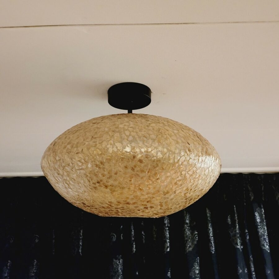 Donkergele plafondlamp van Lichy met natuurlijke schelpenafwerking, geschikt voor woonkamer of eetkamer, creëert warme sfeer, unieke design en elegante uitstraling.