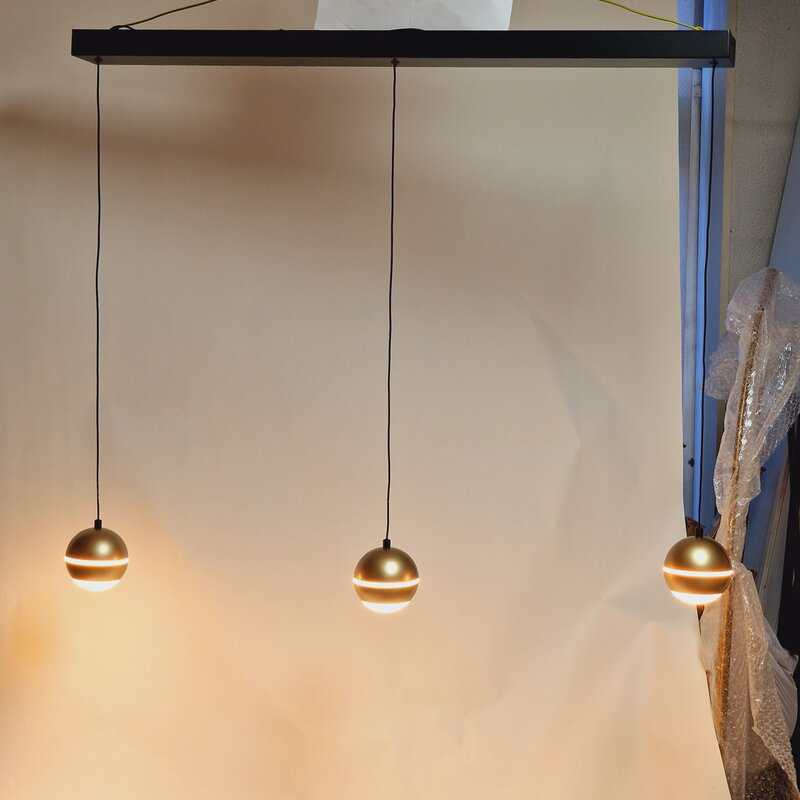 Gouden moderne hanglampen met drie spherevormige lampenkapjes, stijlvolle verlichting voor een eigentijds interieur.